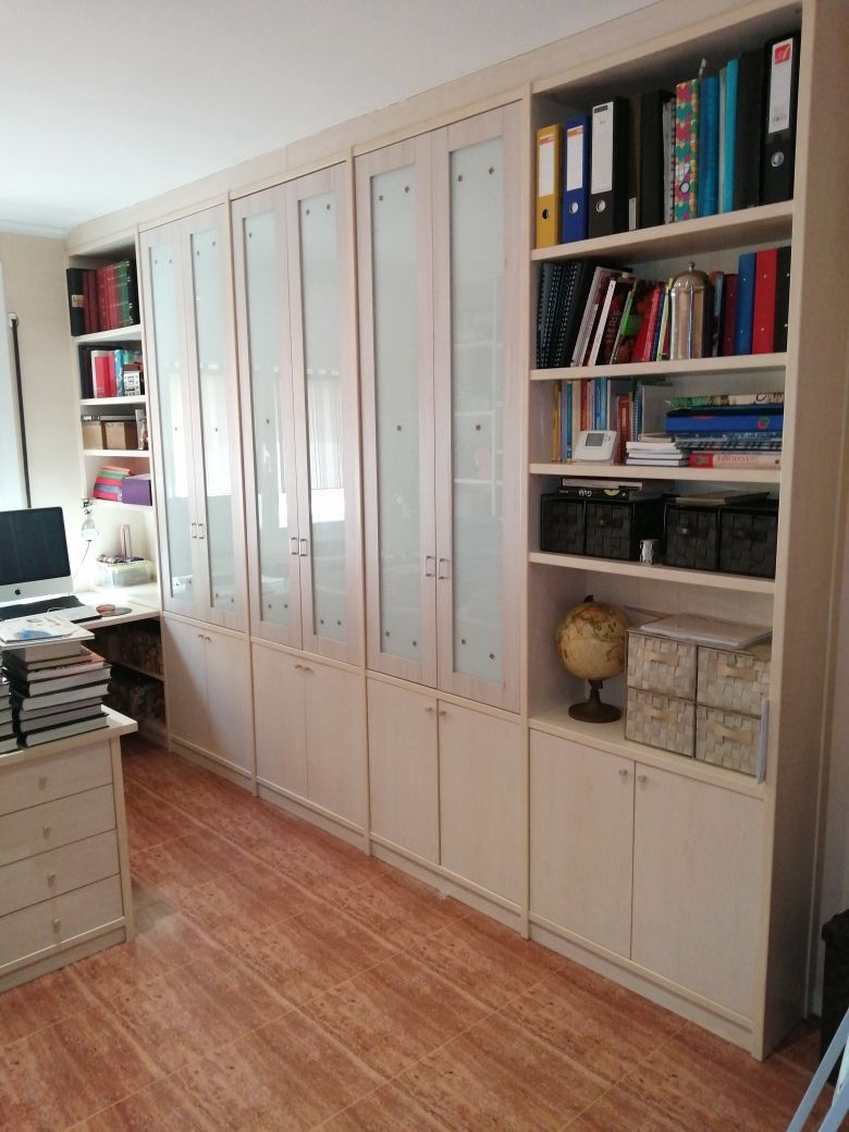 Gabinetes empotrados de color crema con puertas de vidrio esmerilado y estanterías abiertas, en un entorno de oficina en casa.