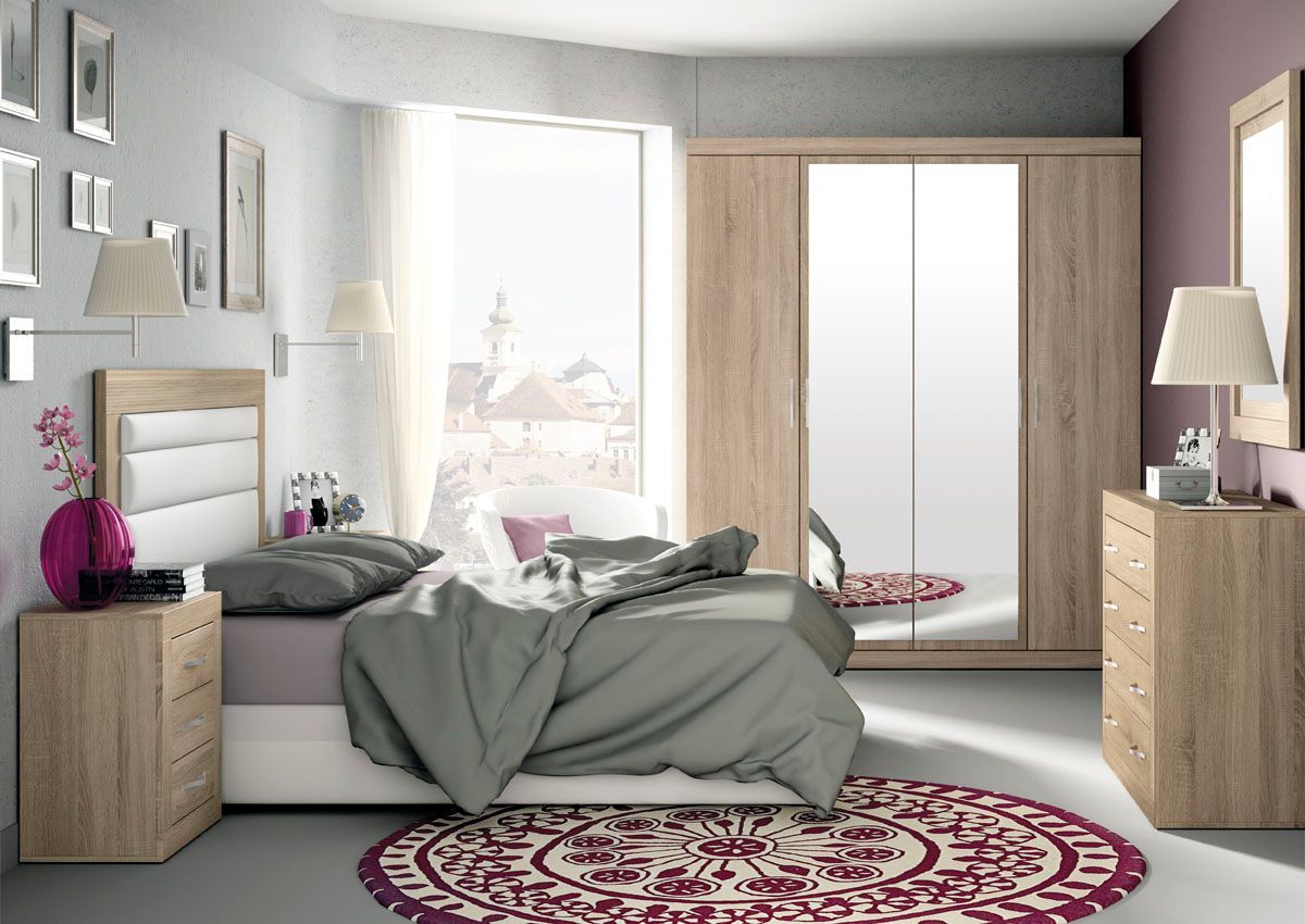 Dormitorio con cama, muebles de madera, espejo grande, alfombra redonda, ventana y detalles en rosa y morado.