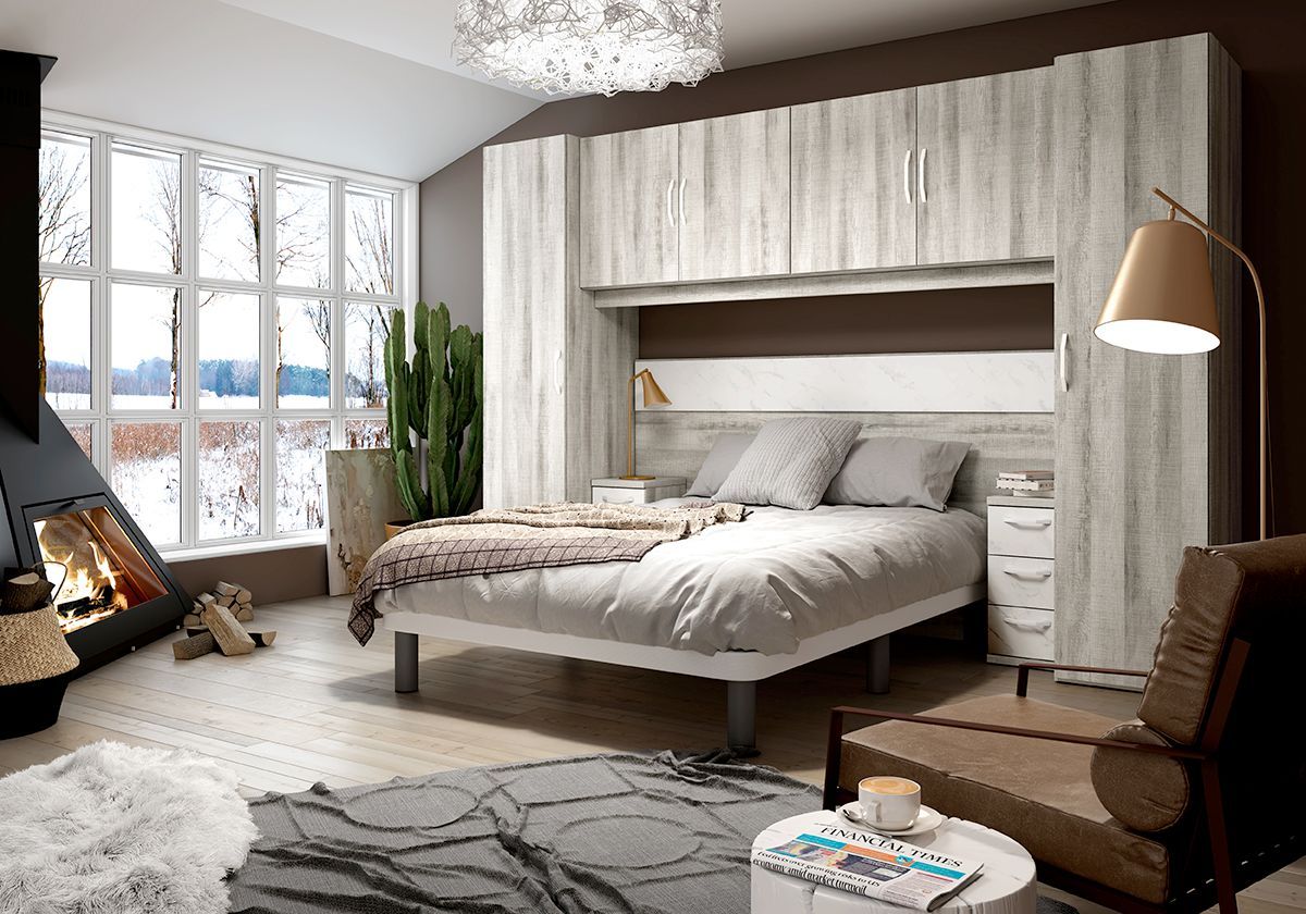 Acogedor dormitorio con cama, chimenea y un gran ventanal con vistas a un paisaje nevado. Tonos neutros y detalles en madera.