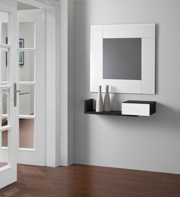 Espejo cuadrado con marco blanco sobre un estante negro con decoración en una pared gris.