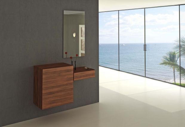 Tocador moderno de madera con espejo sobre pared gris, al lado de una ventana con vista al mar.