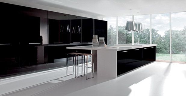 Cocina moderna con gabinetes negros, isla blanca y grandes ventanales que dan a una escena exterior luminosa.