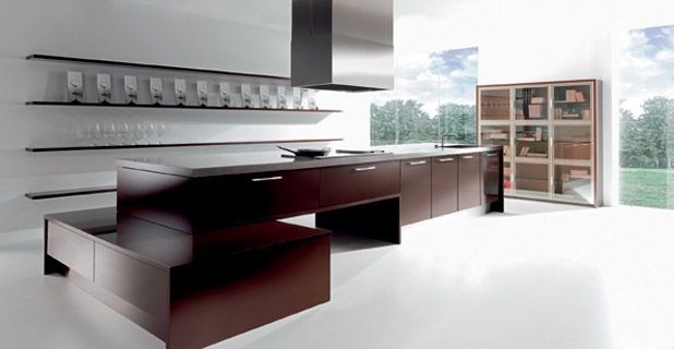 Cocina moderna con gabinetes de color marrón oscuro, isla y estantes abiertos sobre un fondo blanco.