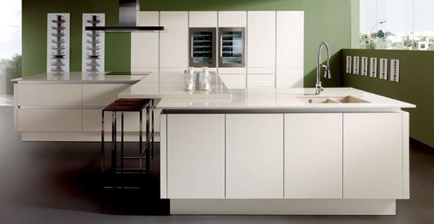 Cocina moderna con gabinetes blancos, dos islas, refrigeradores para vinos y una pared verde.