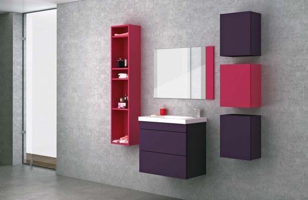 Baño moderno: muebles de pared de color morado y rosa, espejo rectangular, estante alto de color rosa y un lavabo contra una pared gris.