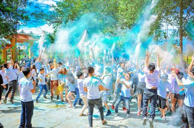Un grupo grande de personas está bailando y lanzando polvo azul al aire.