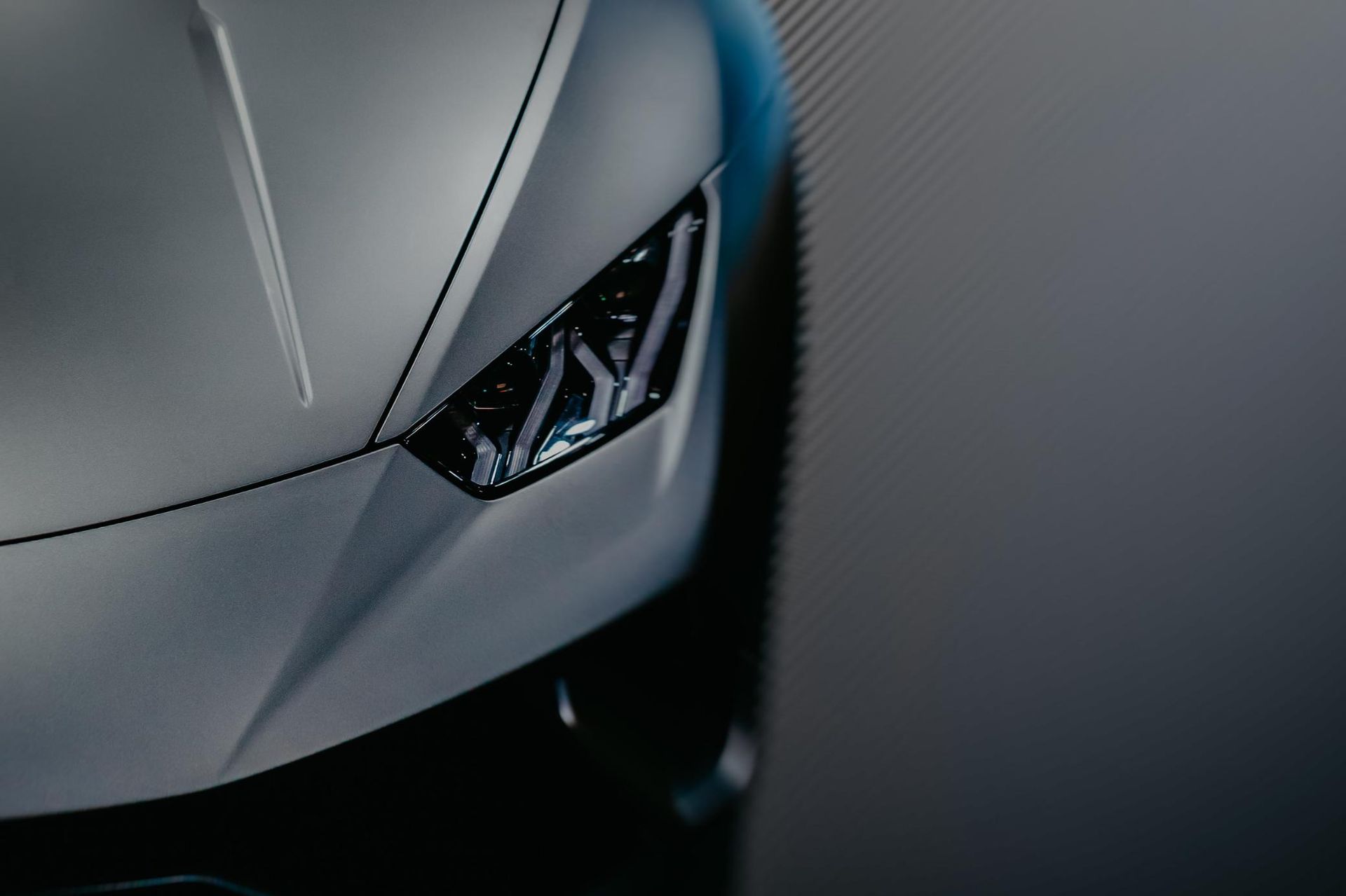 Primer plano del faro y el capó de un Lamborghini Huracán gris mate.