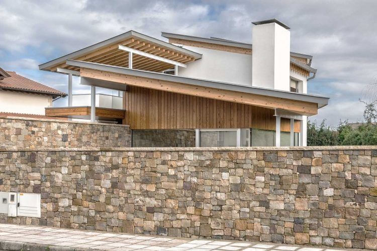 Una casa con pared de piedra y techo de madera