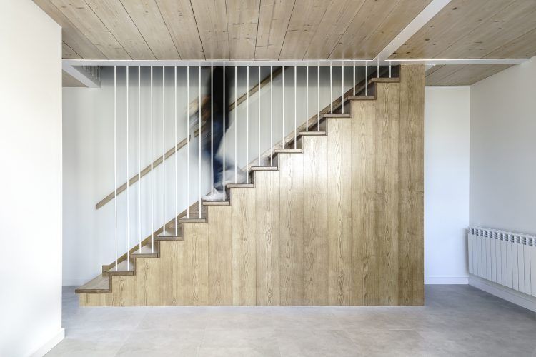 Una habitación vacía con una escalera de madera y una barandilla blanca.