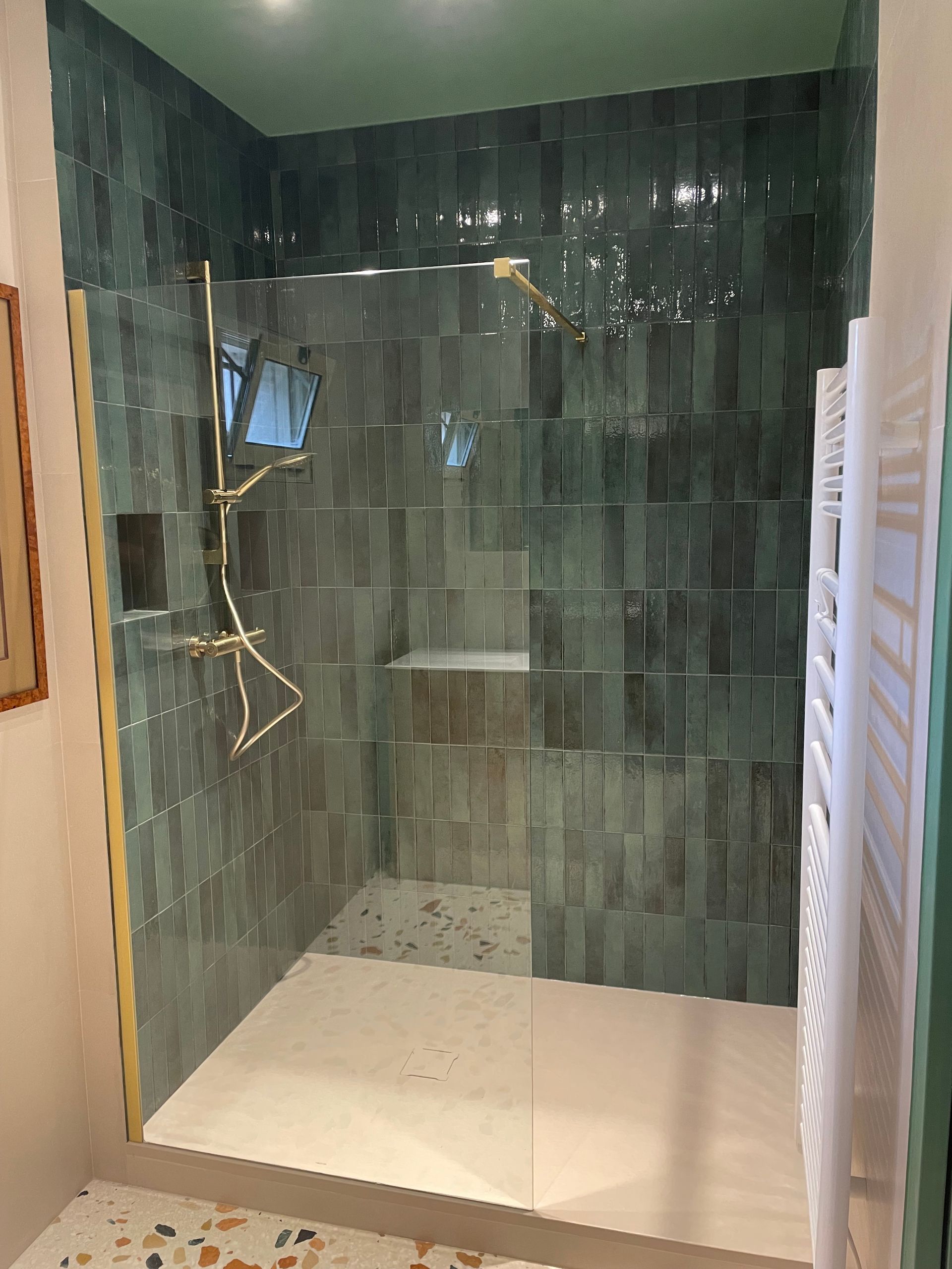 Une douche à l'italienne spacieuse avec un revêtement bleu turquoise et une robinetterie dorée.