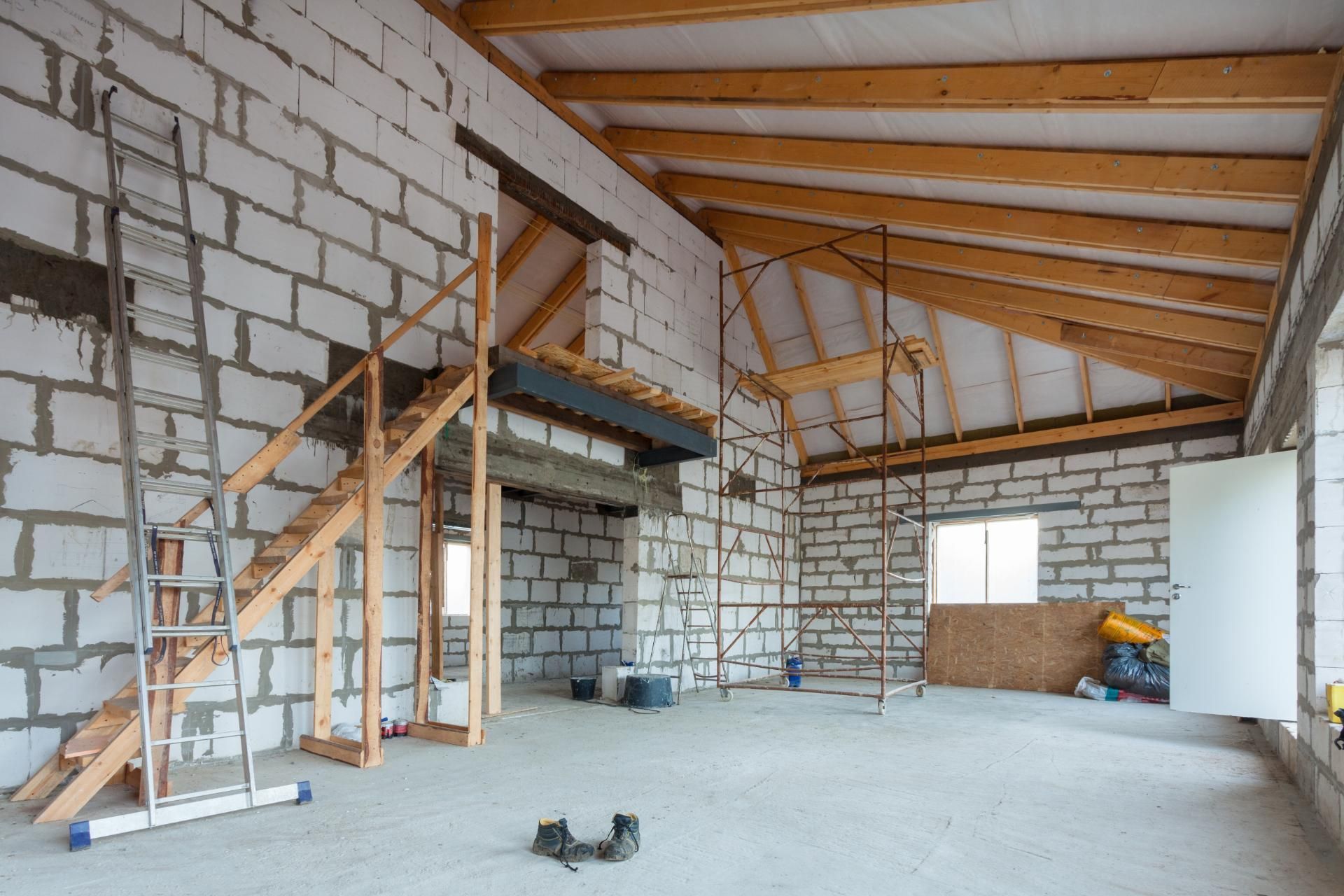 ein leerer Raum mit einer Holztreppe und einer Leiter