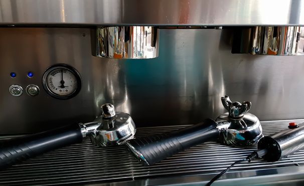 Un primer plano de una máquina de café de acero inoxidable con dos asas.