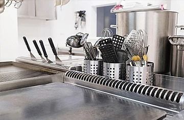 Una encimera de cocina con ollas, sartenes y utensilios encima.