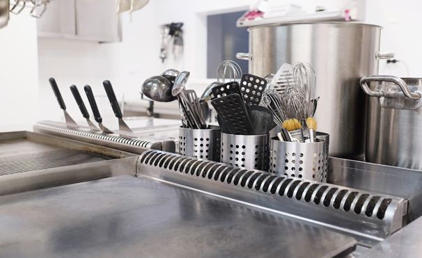 Una encimera de cocina con ollas, sartenes y utensilios encima.