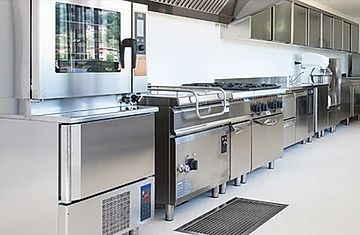 Una cocina con electrodomésticos de acero inoxidable y una alfombra negra en el piso.