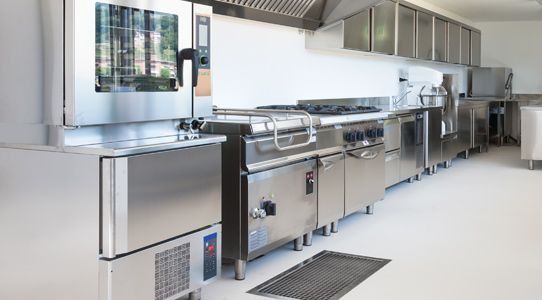 Una cocina con electrodomésticos de acero inoxidable y una alfombra negra en el piso.