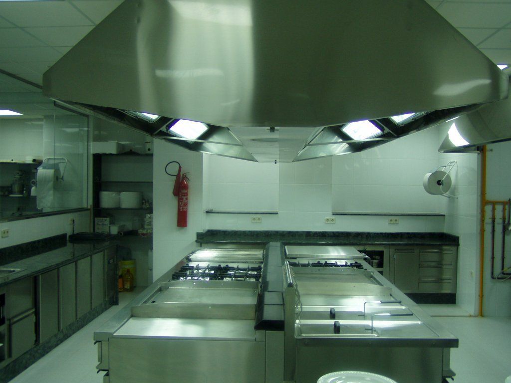 Una cocina con electrodomésticos de acero inoxidable y un extintor de incendios en la pared.