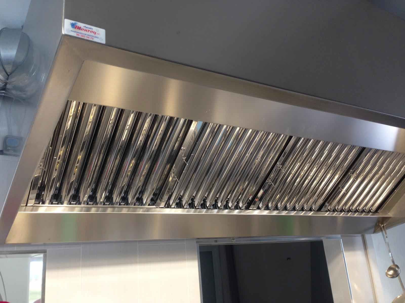 Una campana de acero inoxidable cuelga del techo de una cocina.