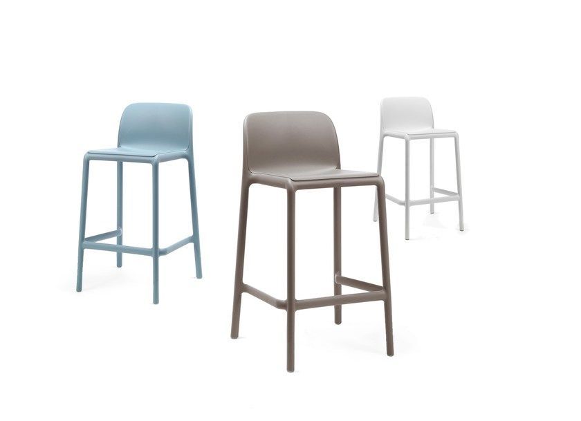 Tres taburetes de bar de diferentes colores están sentados uno al lado del otro sobre un fondo blanco.