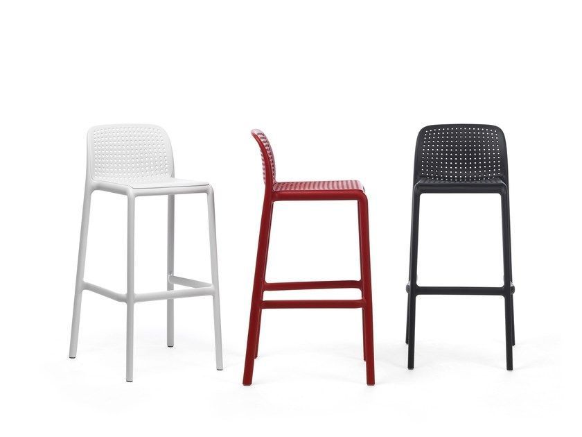 Tres taburetes de bar de diferentes colores están uno al lado del otro sobre un fondo blanco.