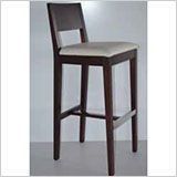 Un taburete de bar de madera con un cojín blanco está sobre una mesa.