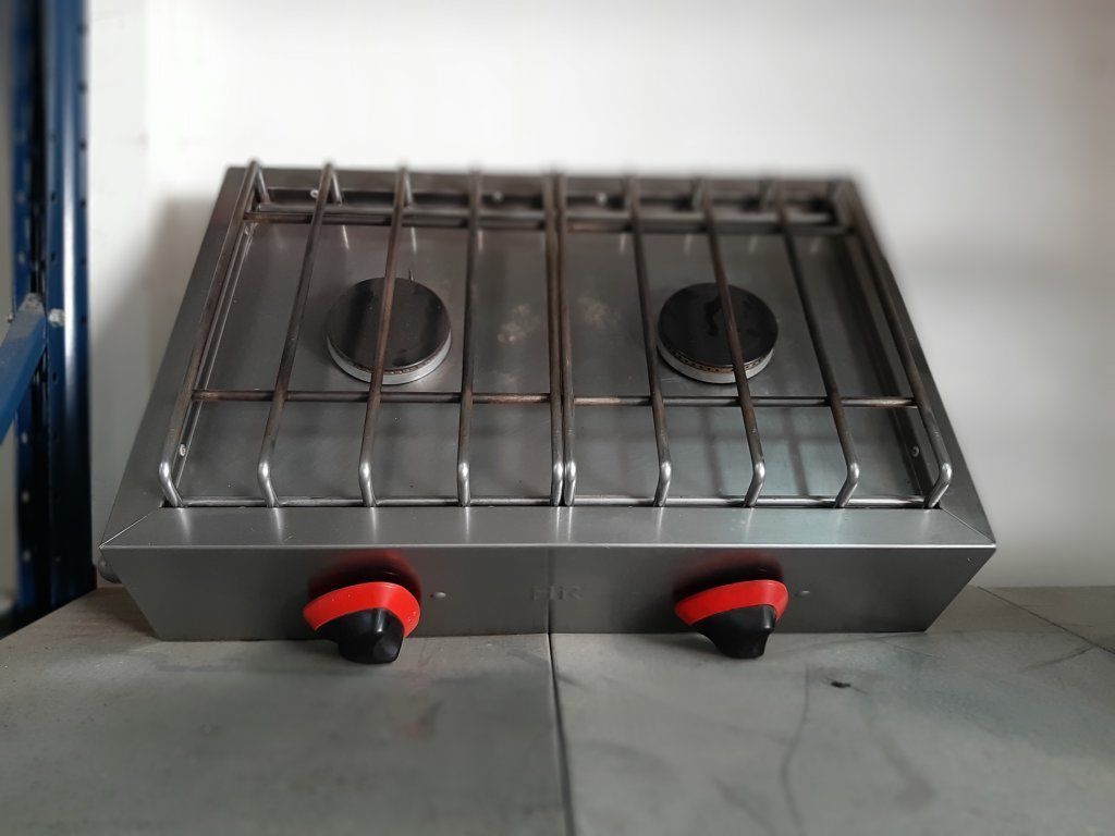 Una estufa de gas de acero inoxidable con dos quemadores y perillas rojas.