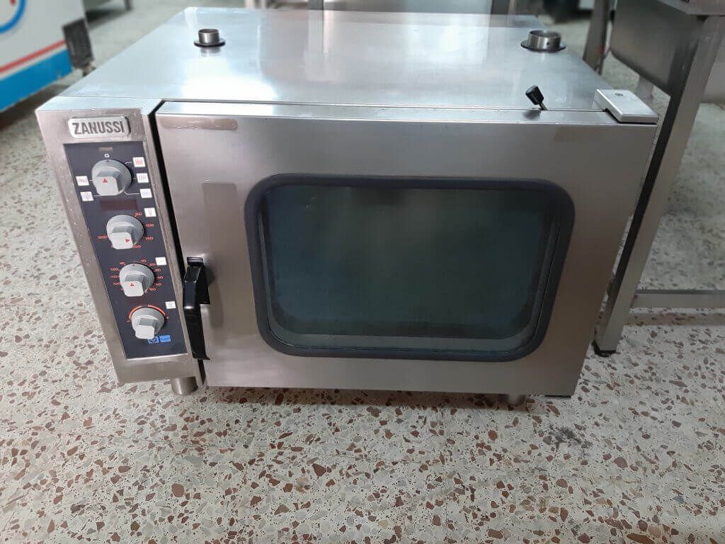 Un horno de acero inoxidable está sobre un suelo de baldosas.