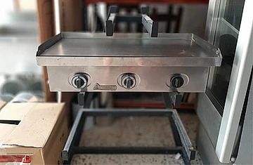 Una parrilla de acero inoxidable está sobre una mesa al lado de una caja.
