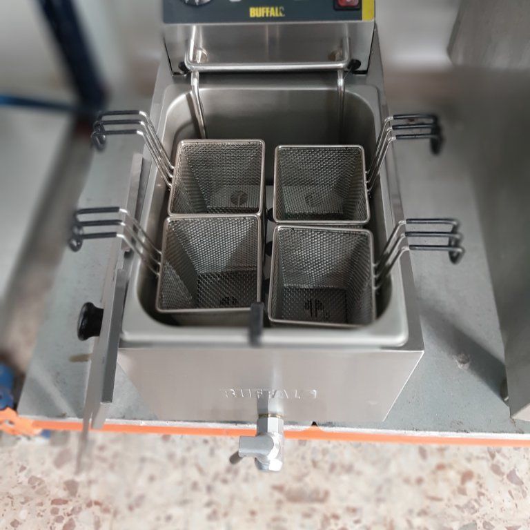 Una freidora de acero inoxidable con cuatro cestas en su interior.