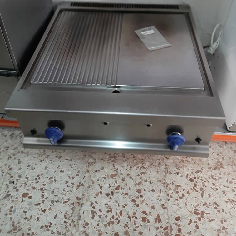 Una parrilla de acero inoxidable está colocada sobre un suelo de baldosas.