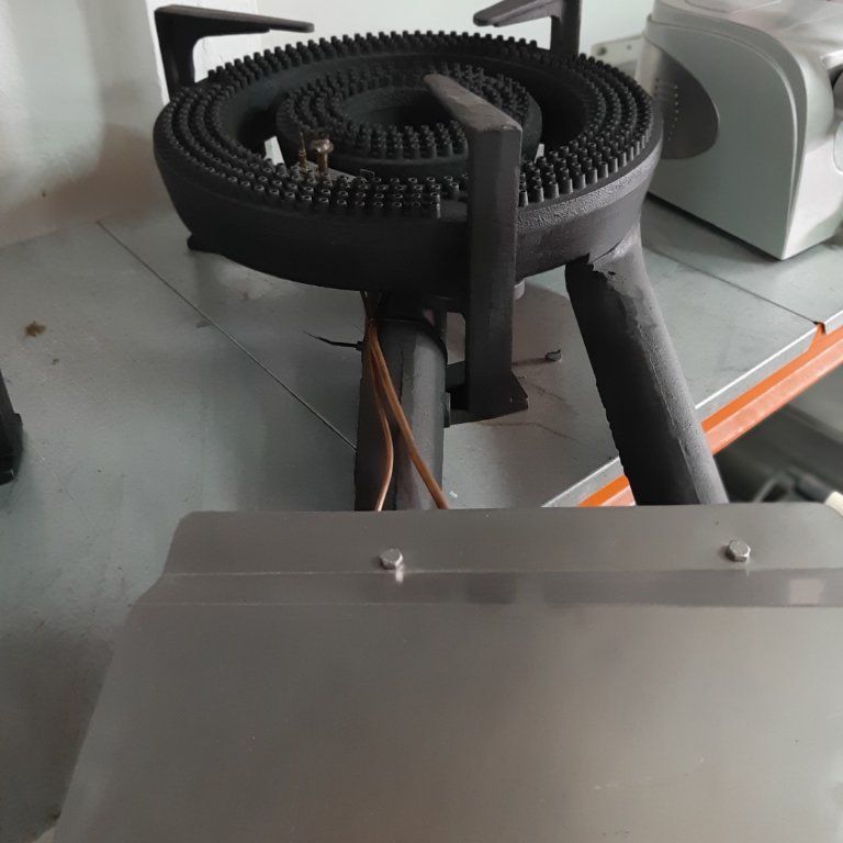 Una estufa de gas está colocada encima de un estante de metal.