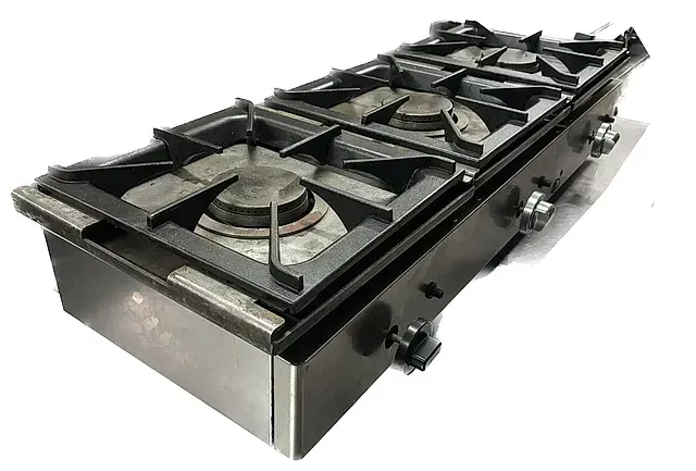 Una estufa de gas con cuatro quemadores está sobre una superficie blanca.