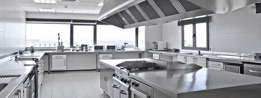 Una fotografía en blanco y negro de una gran cocina comercial con electrodomésticos de acero inoxidable.
