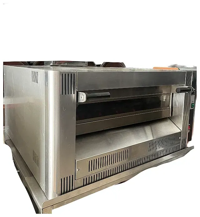 Un horno de pizza de acero inoxidable está sobre una mesa blanca.