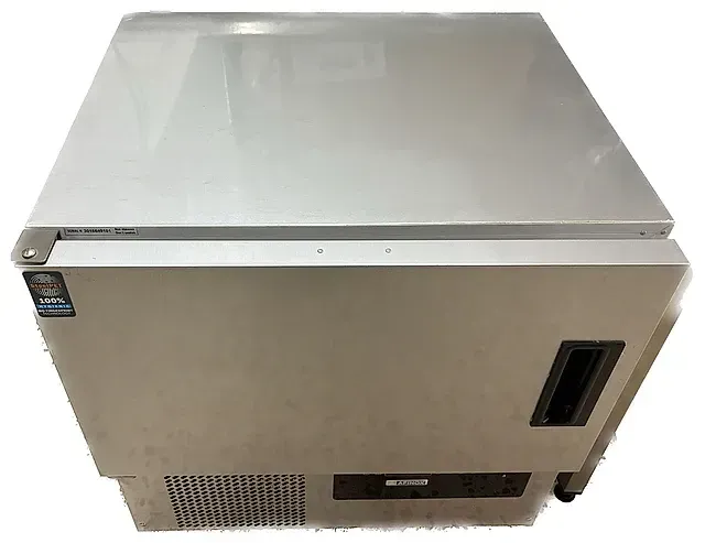 Un refrigerador de acero inoxidable está sentado sobre una superficie blanca.