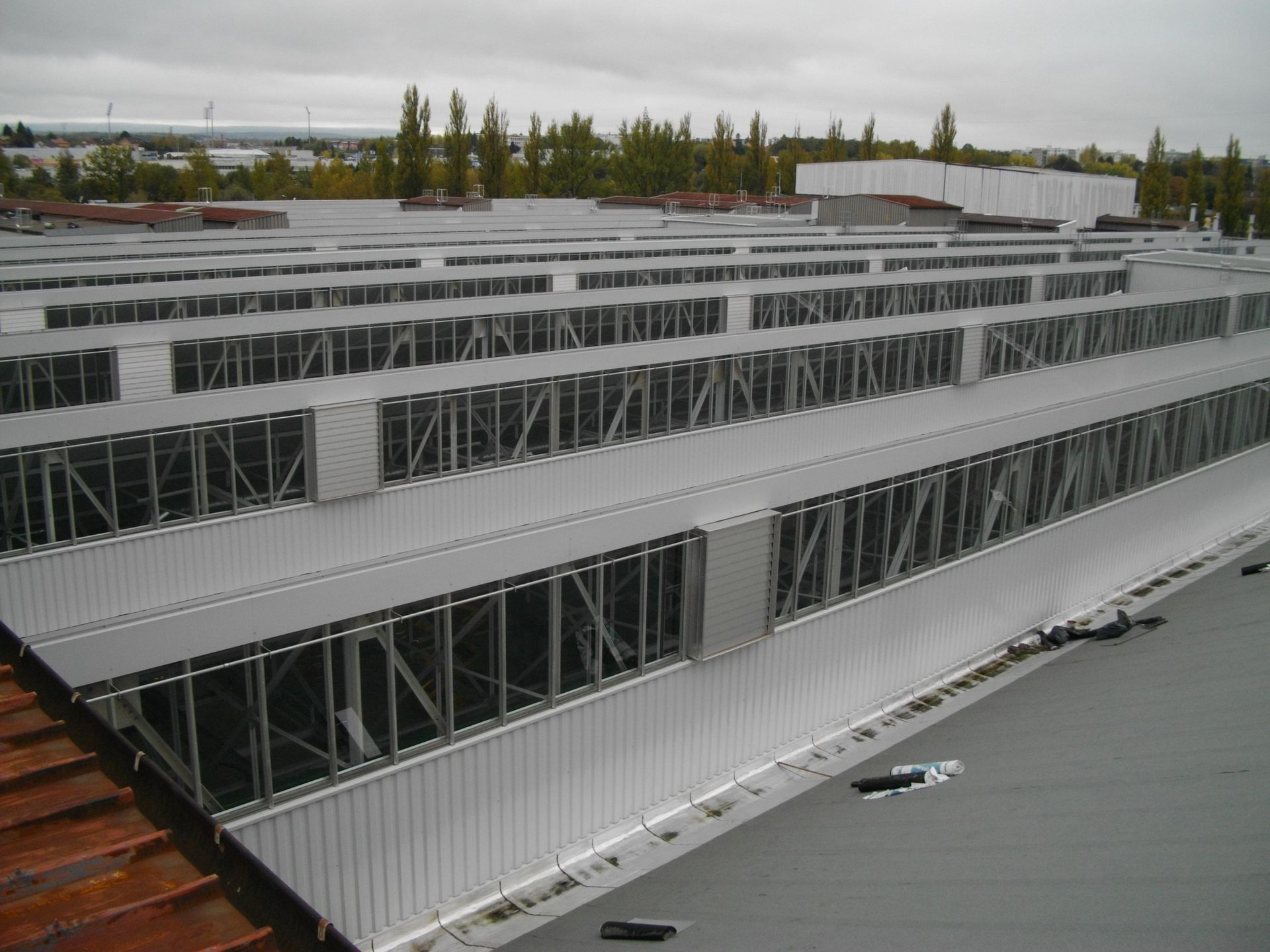 Toiture métallique d'un bâtiment industriel avec de multiples structures de ventilation sous un ciel nuageux.
