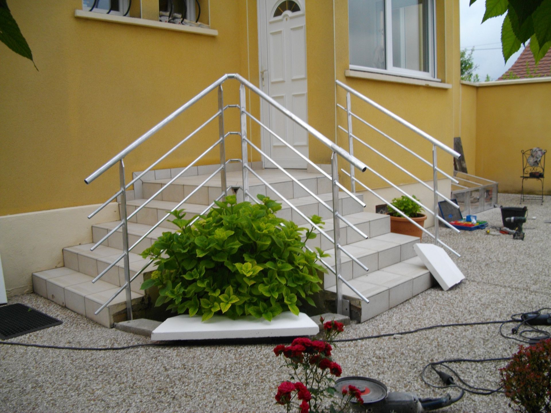 Un escalier avec une rampe métallique mène à une porte blanche.