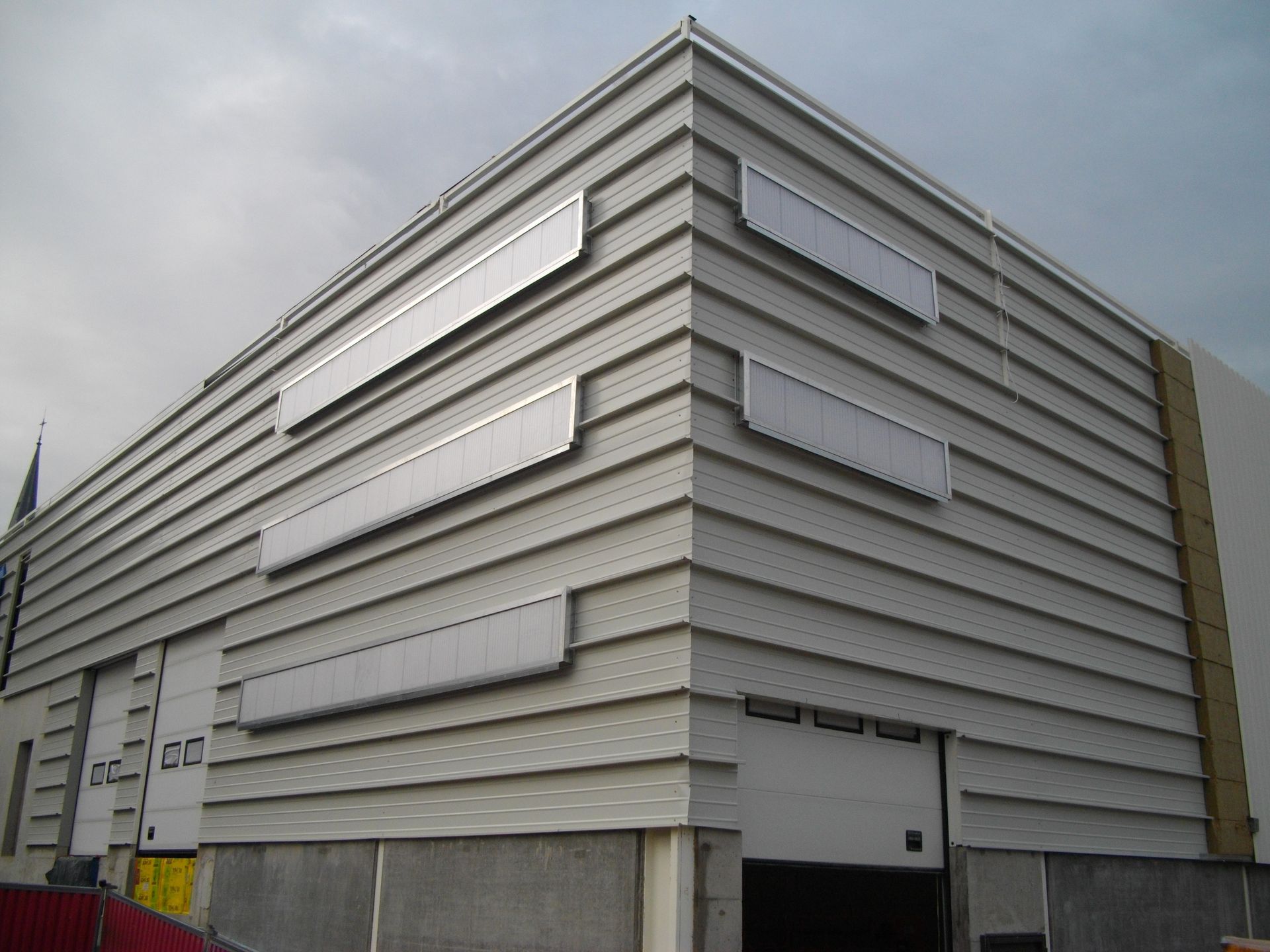 Extérieur gris d'un bâtiment industriel avec bardage horizontal et panneaux argentés.