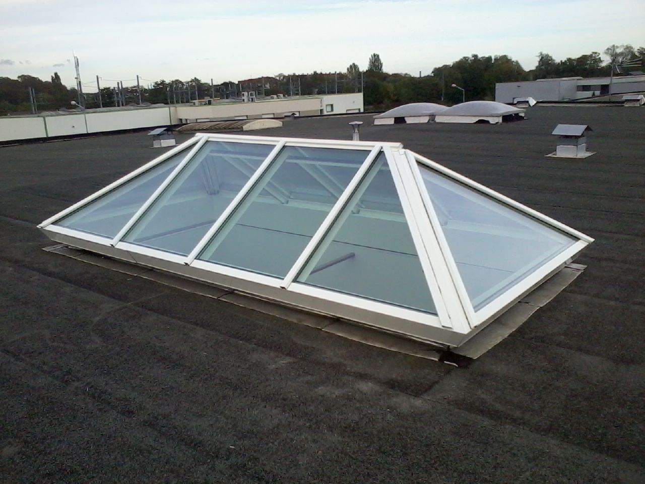 Grande verrière rectangulaire sur un toit plat noir. 