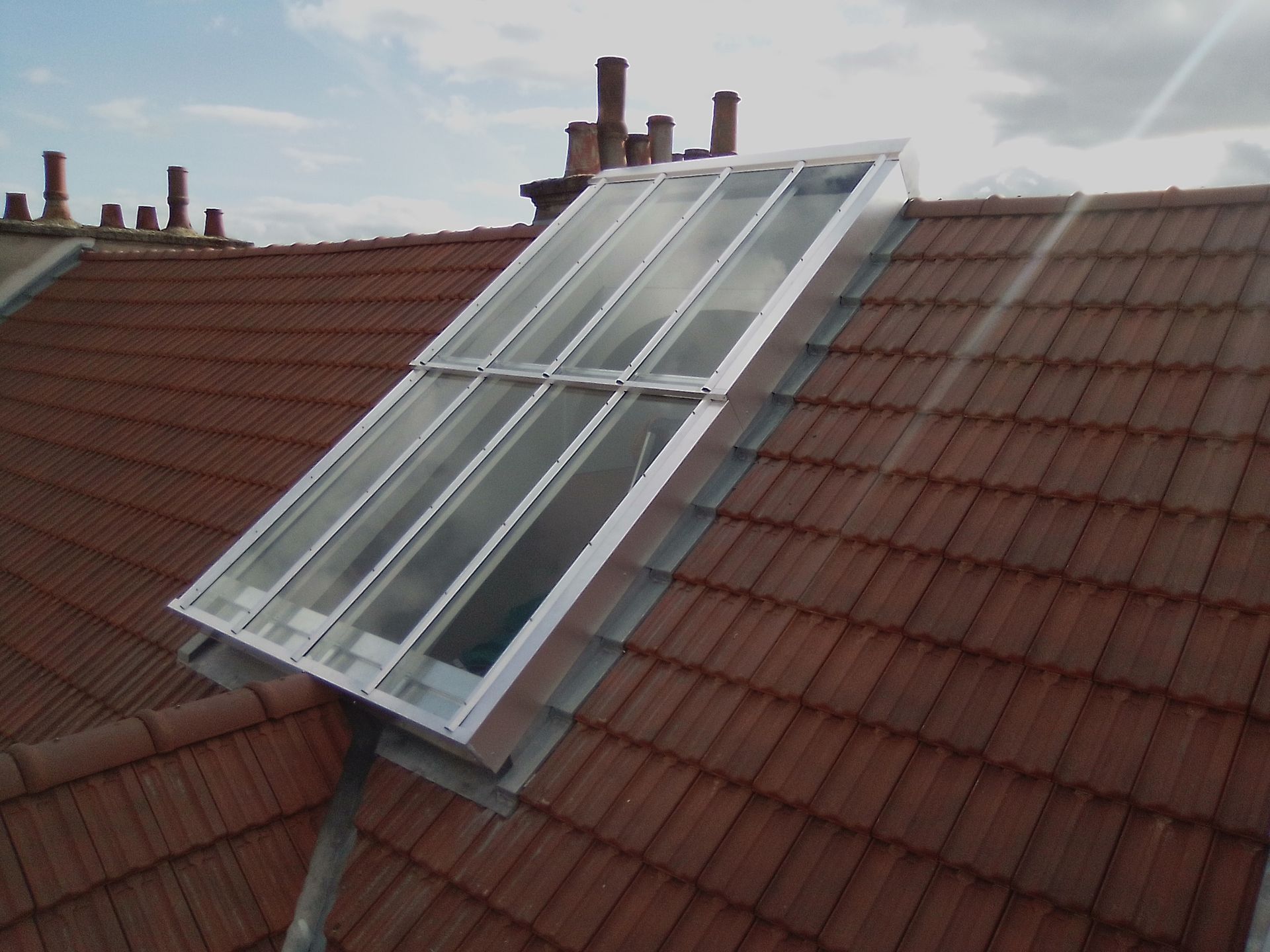 Intérieur d'entrepôt vide avec hauts plafonds, puits de lumière et poutres de soutien bleues.