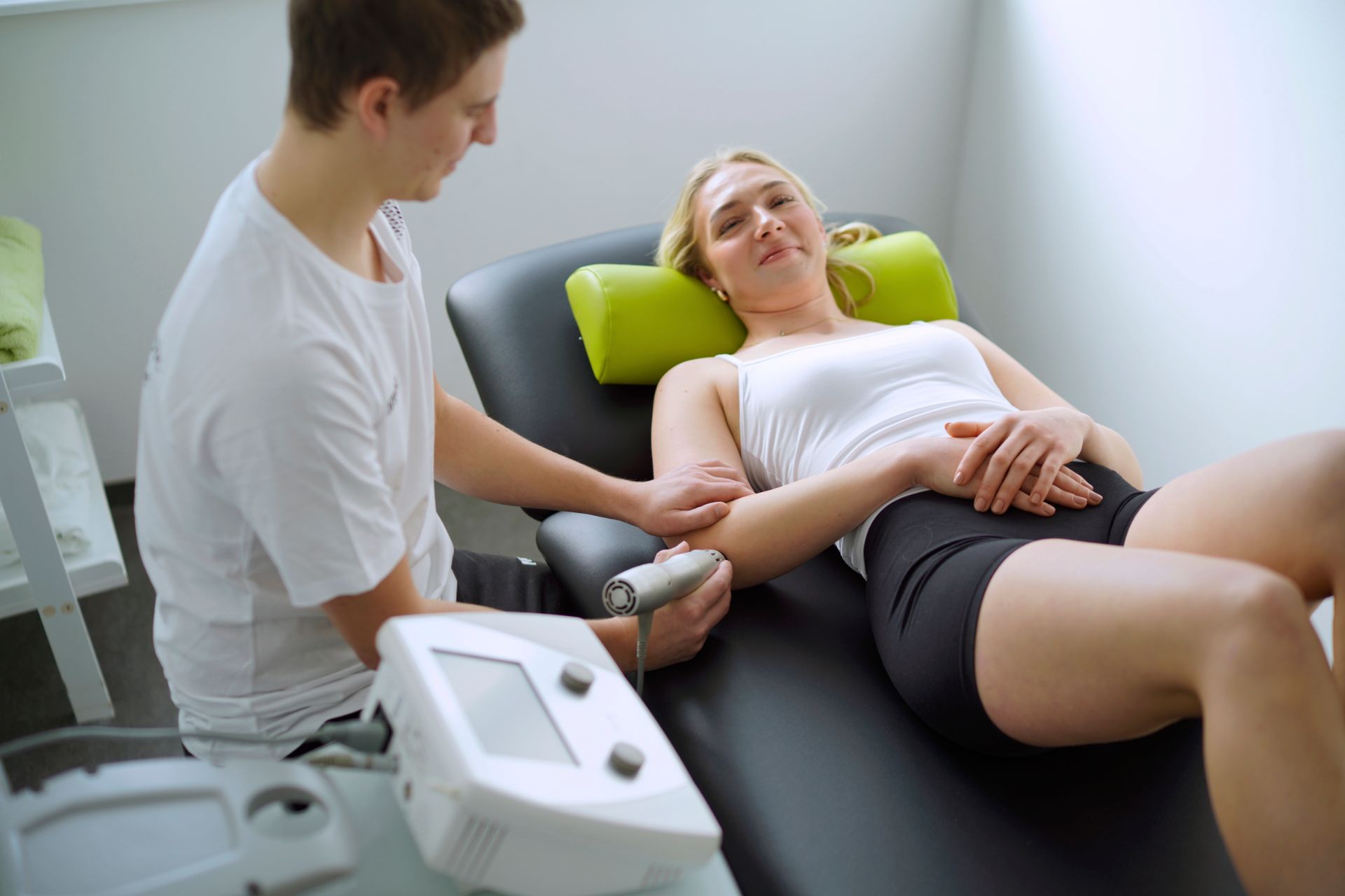 Eine Frau liegt auf einem Bett und wird von einem Mann massiert.