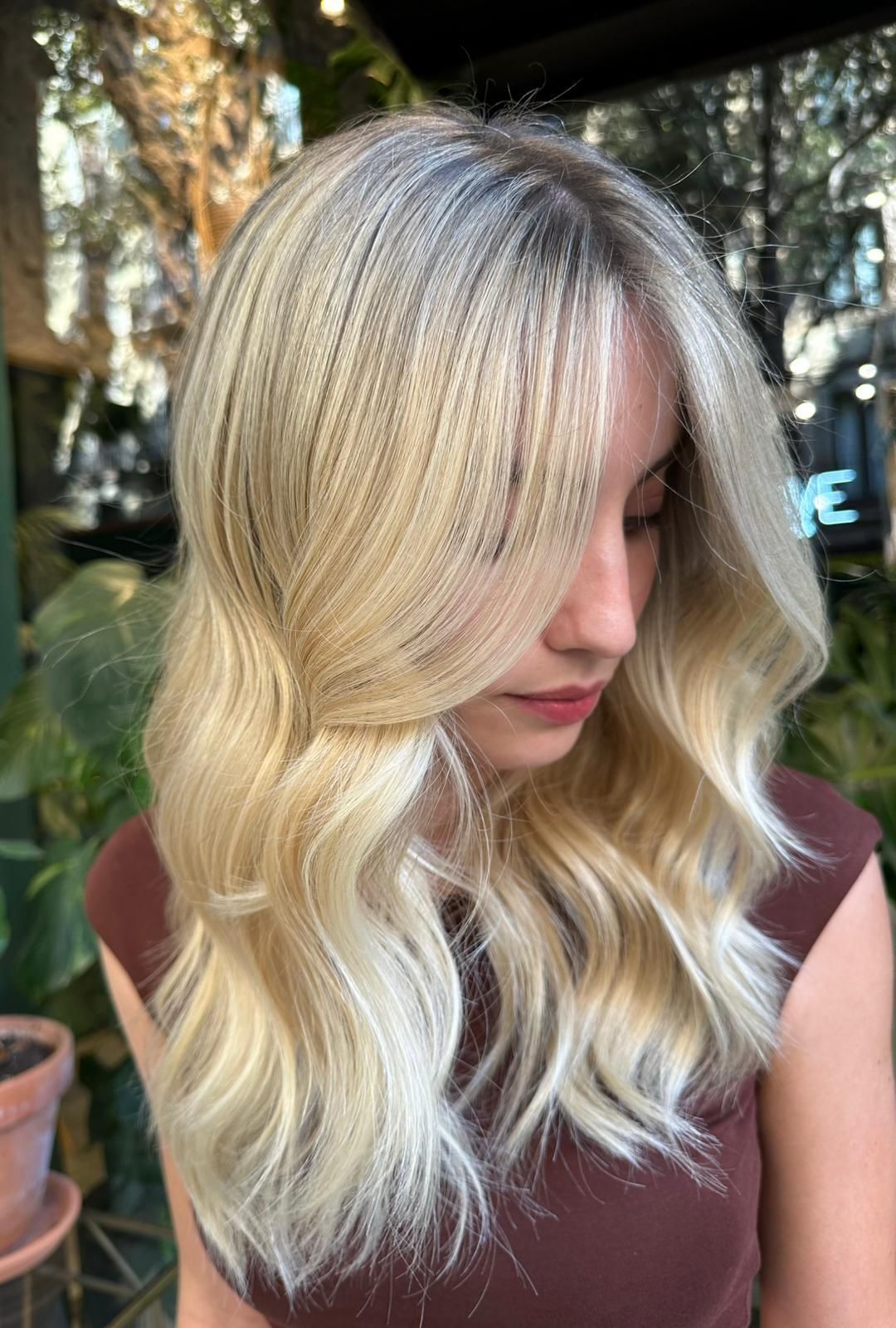 Una mujer con cabello largo y rubio lleva una camisa marrón.