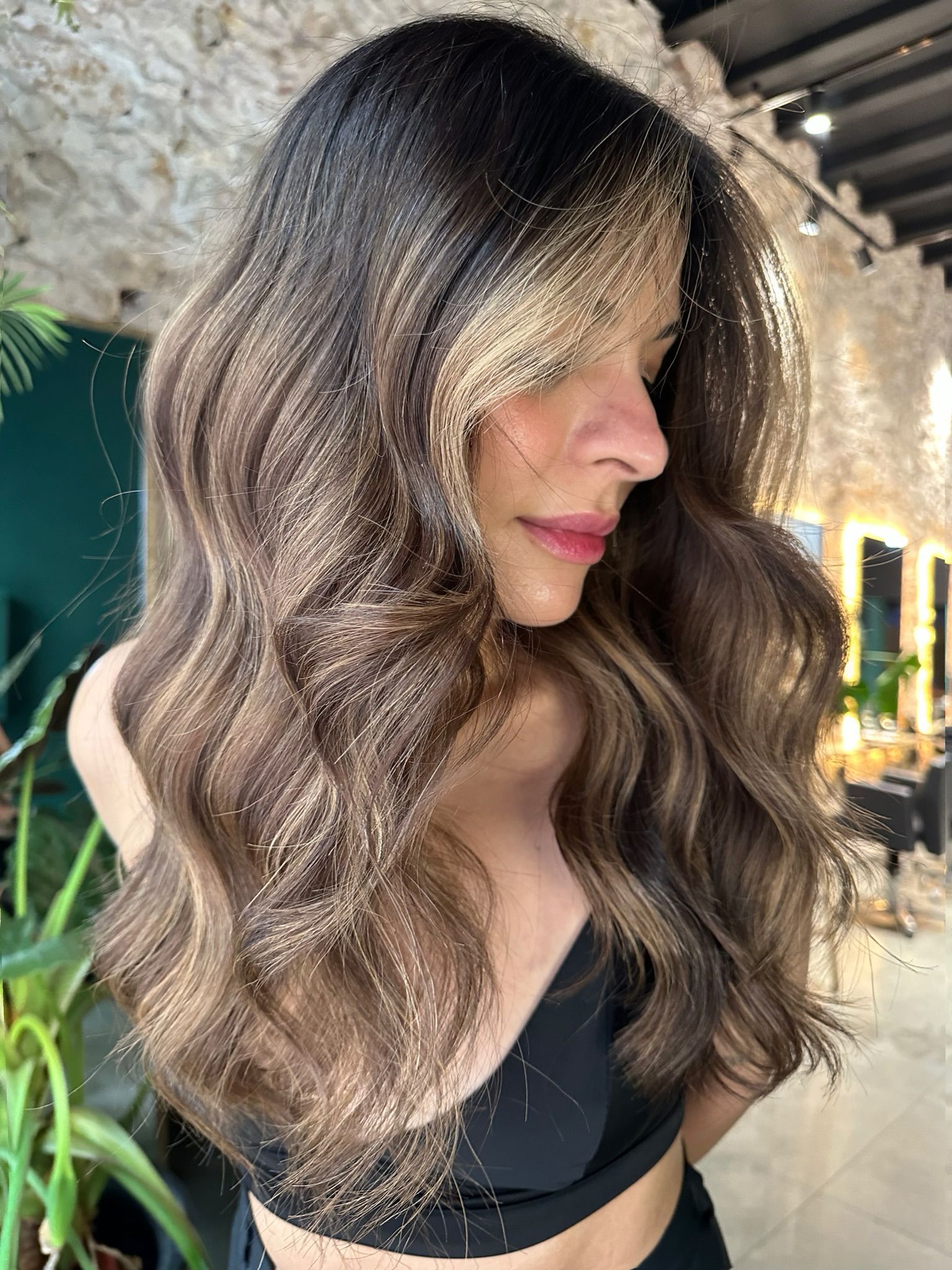 Una mujer con cabello largo y castaño lleva un top corto negro.