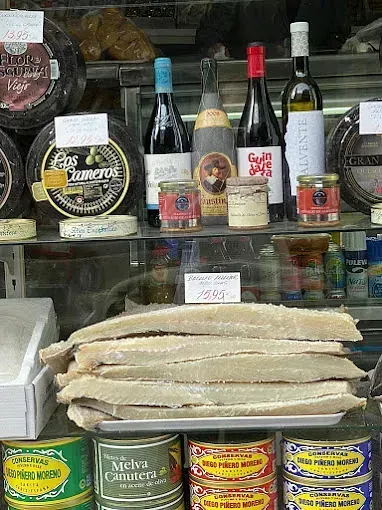 Vitrina con bacalao en salazón, quesos, botellas de vino y conservas.