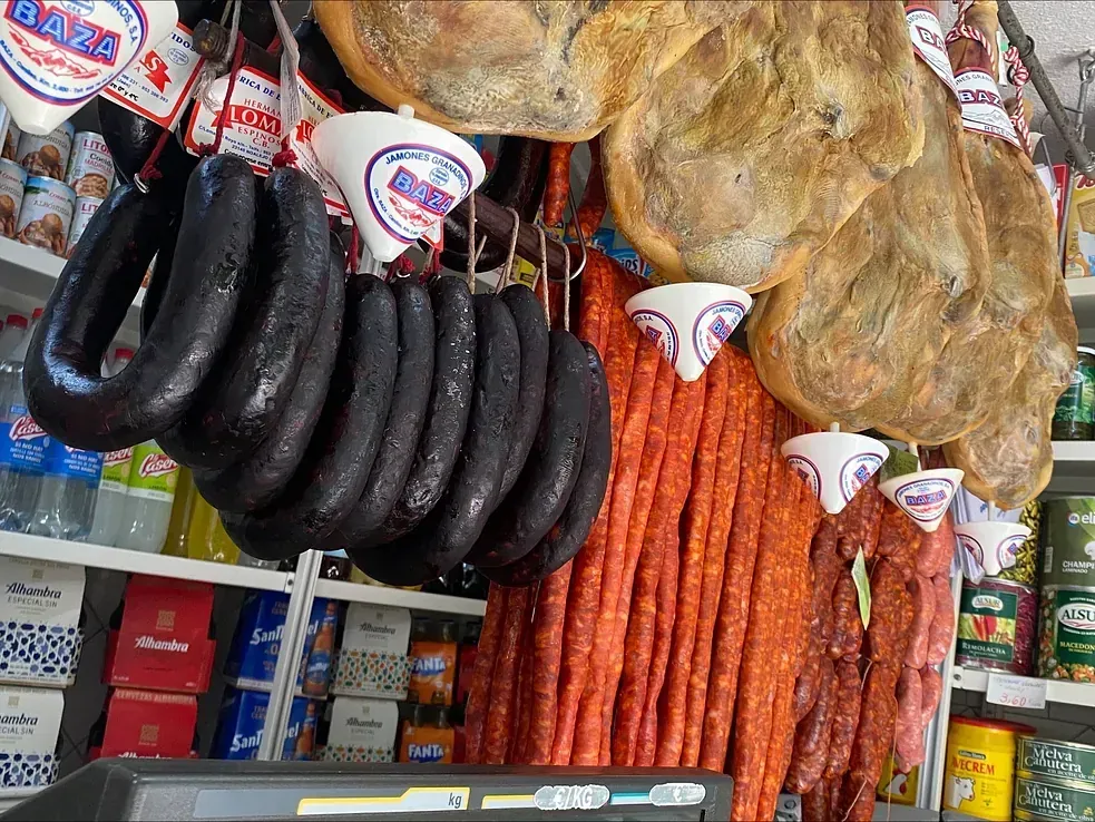 Surtido de embutidos colgados en una tienda: morcillas, chorizos y jamón.
