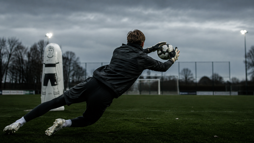 Ein Fußball, der während des Spiels im Tornetz gefangen wurde, im Hintergrund ist das Stadion verschwommen zu sehen.