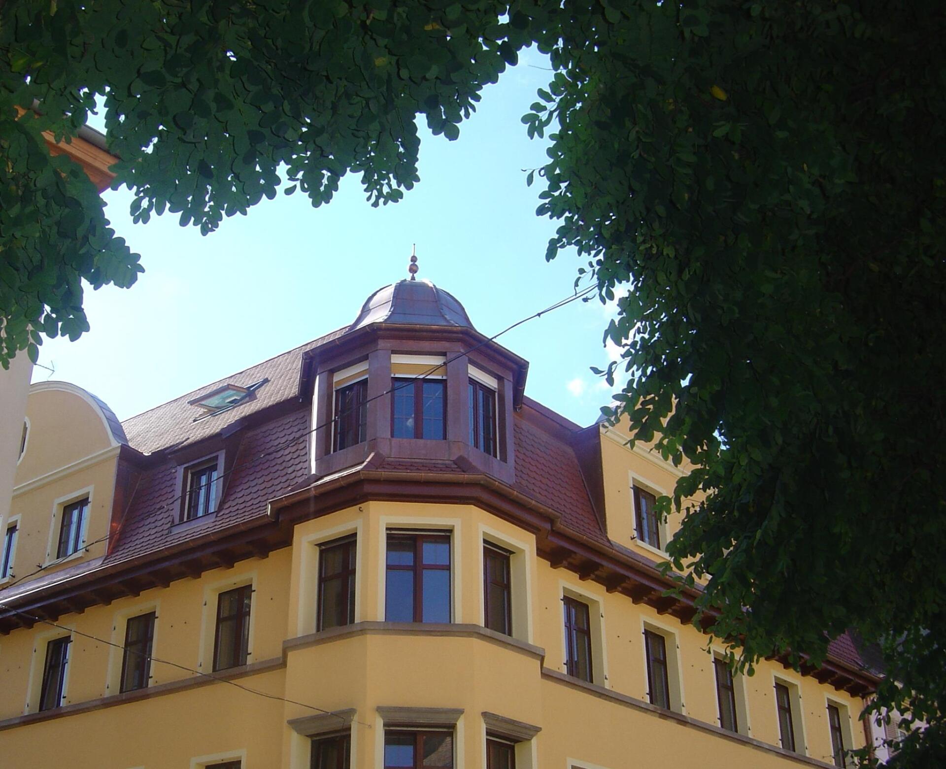 Maison à étages de murs colorés avec coin arrondi légèrement ressortis du bâtiment avec fenêtre