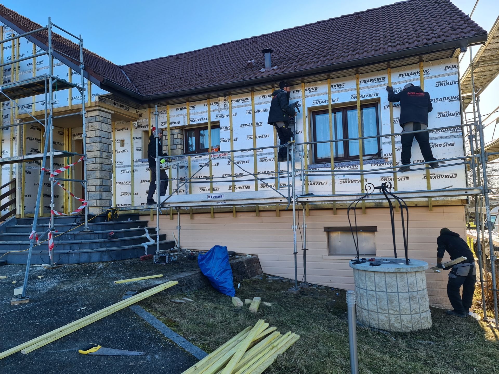 Installation d'isolation de façade par trois ouvriers