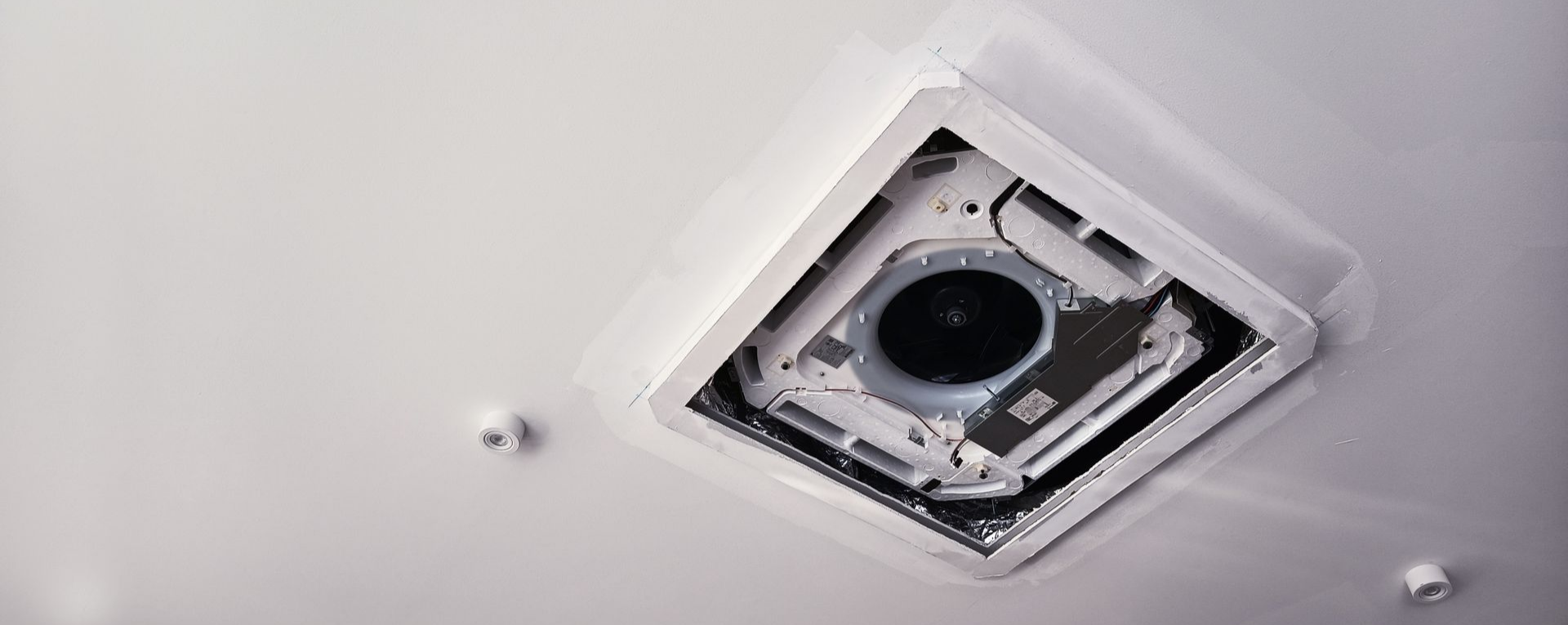 Système de ventilation encastré au plafond blanc, doté d'une ouverture circulaire.