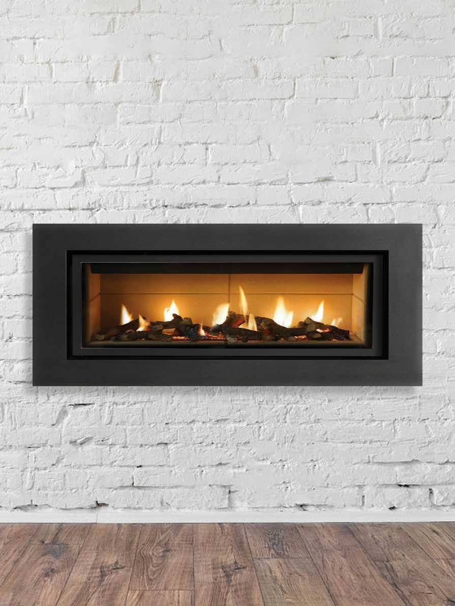 Cheminée à gaz à cadre noir encastrée dans un mur de briques blanches.